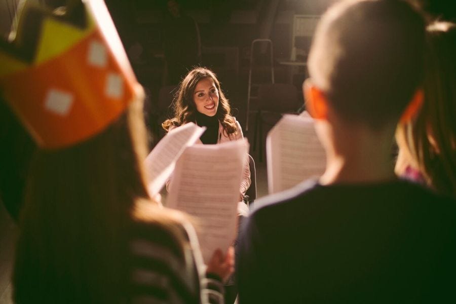 A theater teacher and her students enjoying their rehearsal.