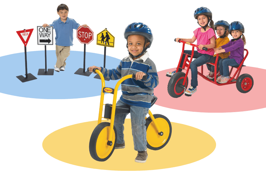 Young preschoolers wearing helmets while riding balance bikes and trikes.