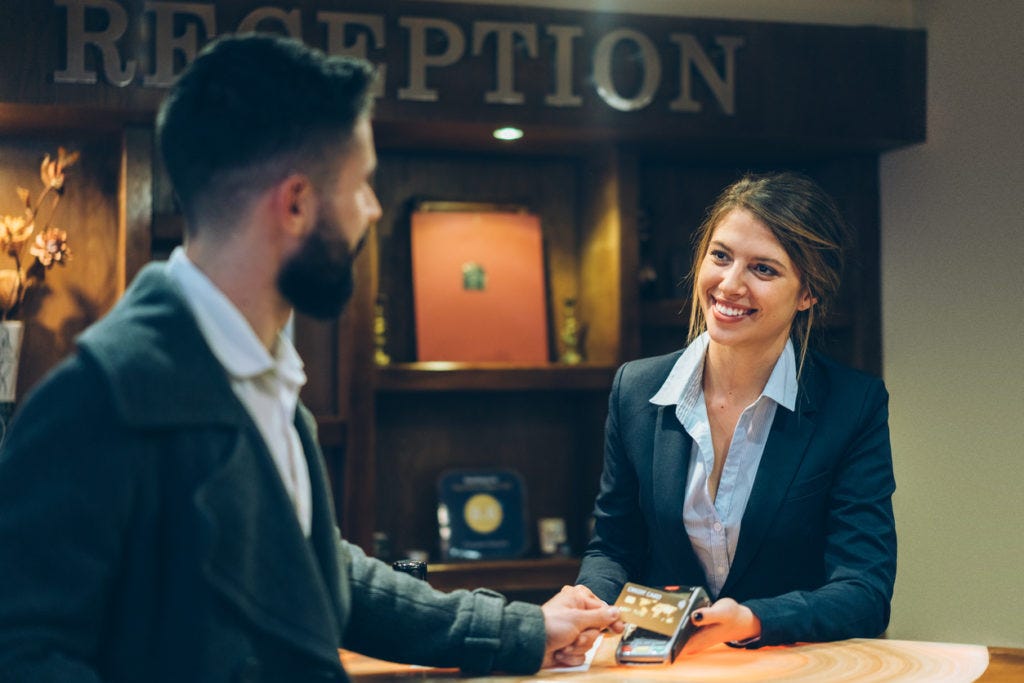 businessman-holding-a-credit-card-on-a-reception-desk-in-front-of-a-receptionist