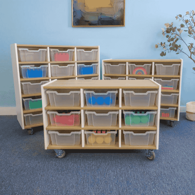 Three mobile storage units of varying heights inside a classroom, each featuring cubbies with clear plastic bins for organized storage.