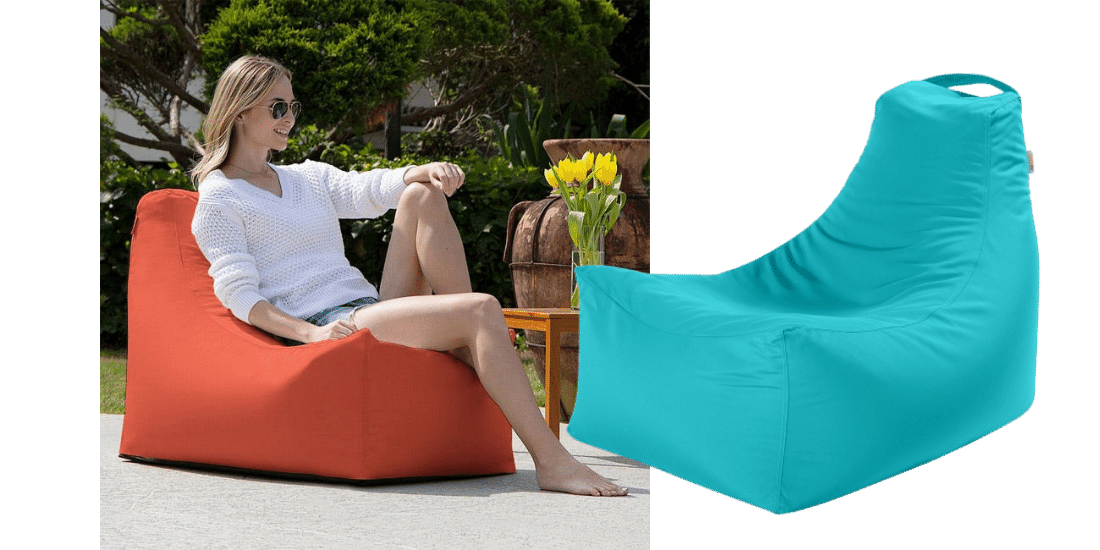 Woman with sunglasses on lounges outside on a orange oversized beanbag. 