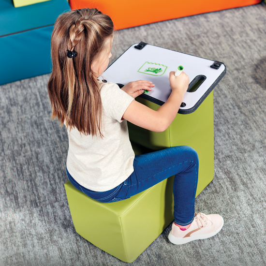 Young student sitting on soft seating while doing class work. 