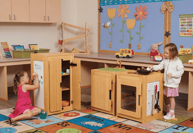Young children engaged in imaginative play at a dramatic play station in an early childhood classroom.