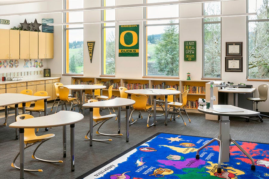 Bright elementary classroom featuring Virco yellow student chairs, curved and rectangular activity tables, classroom storage, and group learning areas.