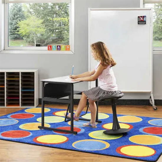 Student sitting at desk with a pendulum foot rest. 