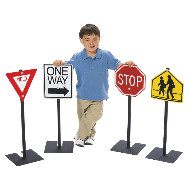 Child standing among play traffic signs for preschool playgrounds. 